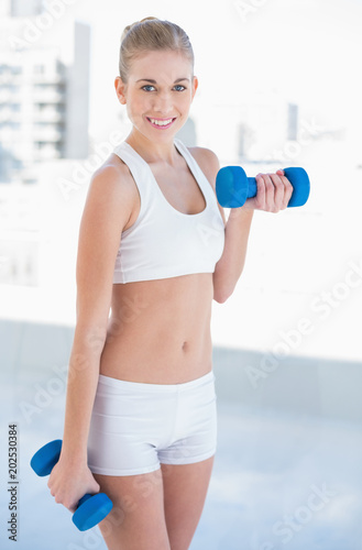 Content young blonde model exercising with dumbbells