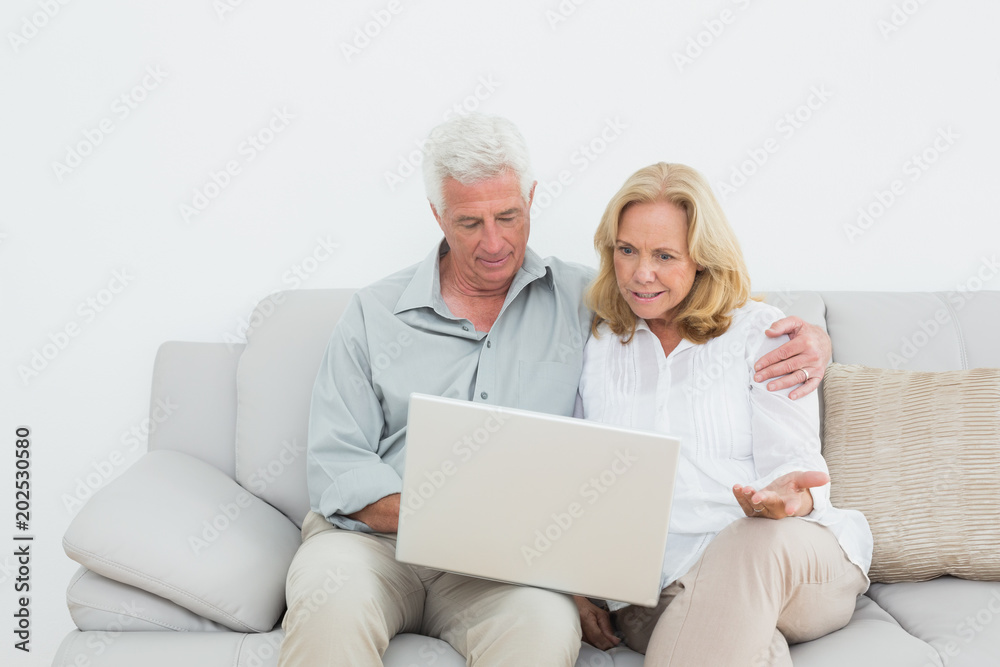 Relaxed senior couple using laptop at home Relaxed senior couple using laptop at home