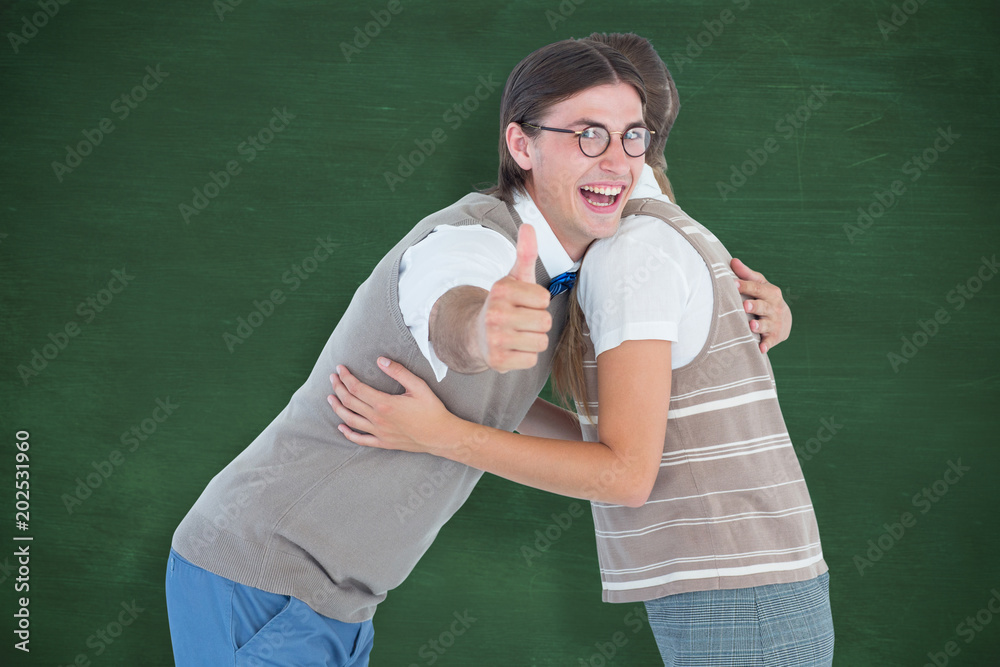 Geeky hipster couple hugging  against green chalkboard