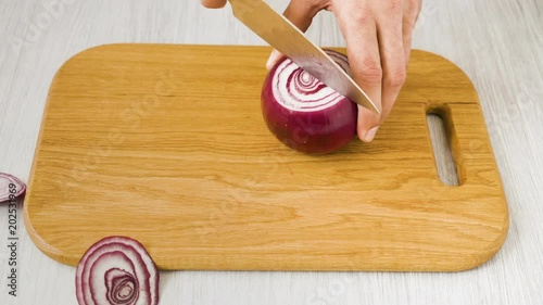 preparetion onion on wooden cutting board. Male hands cut with knife onion photo