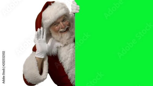 Santa waving from behind a green screen for your logo/text photo