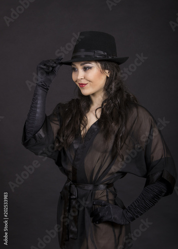 Beautiful young girl in black tunic, black gloves and black hat.