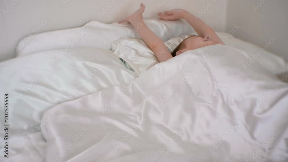 Seven-year-old boy wakes up, hides behind a blanket and sleeps on. Seven-year-old boy wakes up, hides behind a blanket and sleeps on.