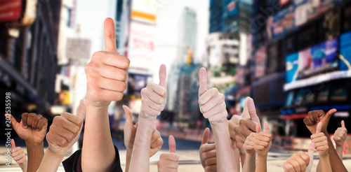 Hands showing thumbs up against blurry new york street