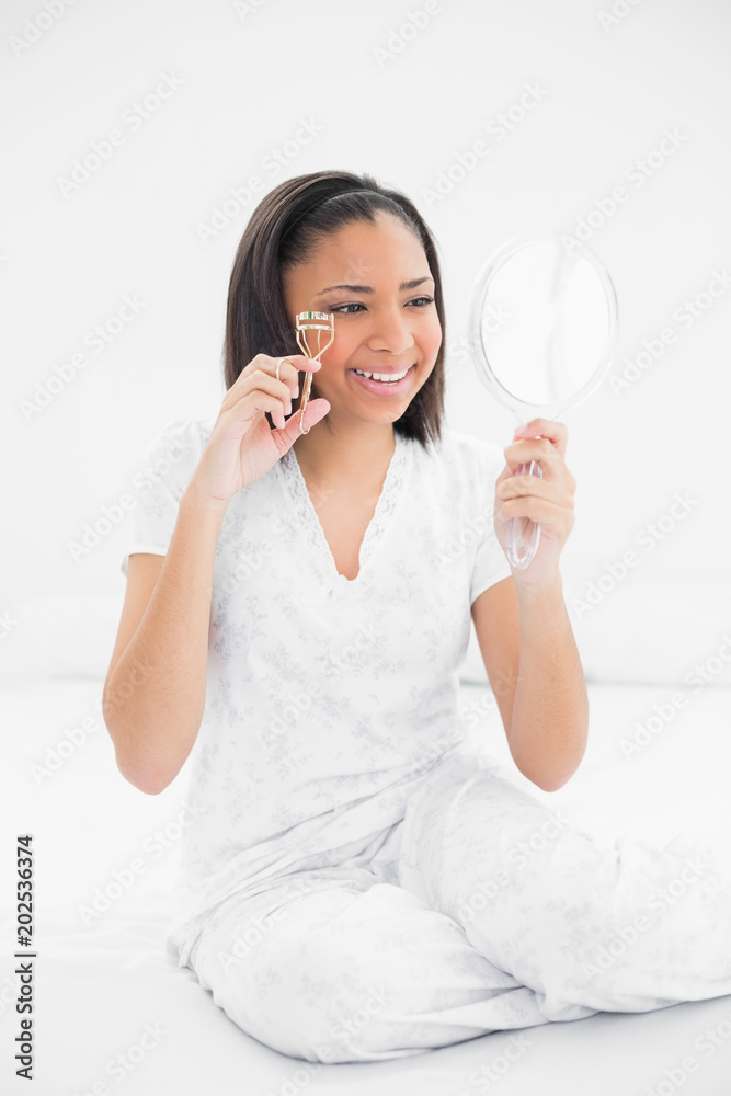 Smiling young dark haired model using eyelash curler Smiling young dark haired model using eyelash curler
