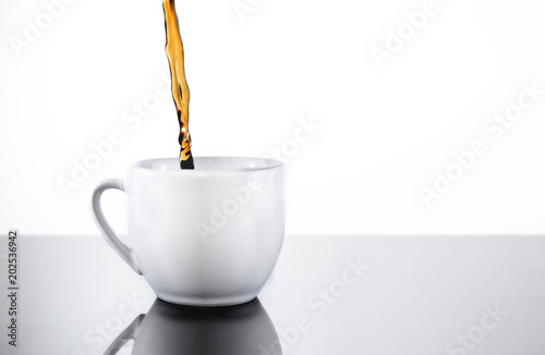 Filling a white porcelain mug cup with fresh, dark black coffee or tea