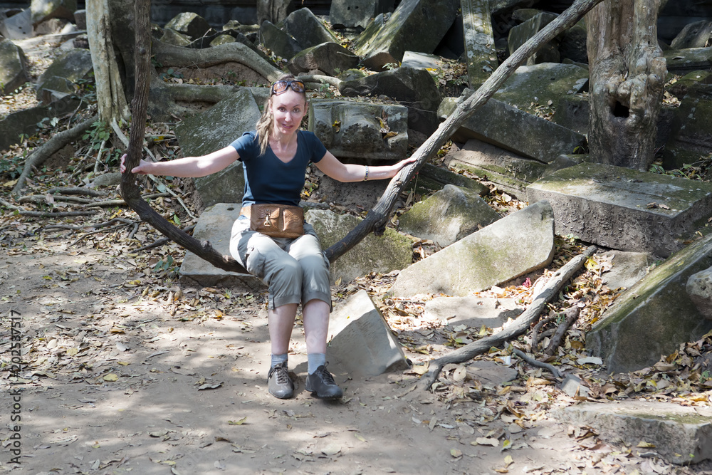 Φωτογραφία The woman, the tourist, shakes on a liana as on a swing on Beng Mealea temple  ruin in the Koh Ker complex, Siem Reap, Cambodia