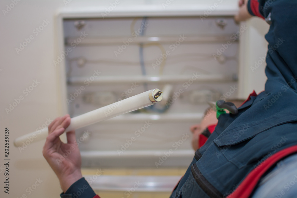 Φωτογραφία Electrician man worker in uniform installing ceiling fluorescent lamp