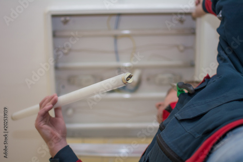Bilde på lerret Electrician man worker in uniform installing ceiling fluorescent lamp