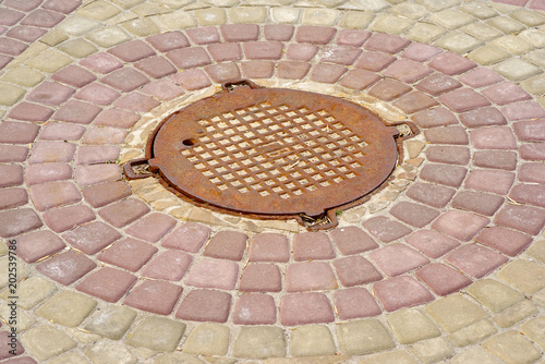 old sewer hatch surrounded by colored tiles