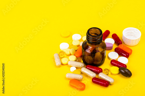Capsules, pills on yellow background. Concept of health and pharmacology