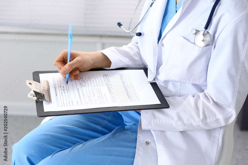 Female doctor filling up medical form on clipboard closeup. Physician finishing up examining his patient in hospital and ready to give a prescription to help. Healthcare, insurance and medicin Female doctor filling up medical form on clipboard closeup. Physician finishing up examining his patient in hospital and ready to give a prescription to help. Healthcare, insurance and medicin