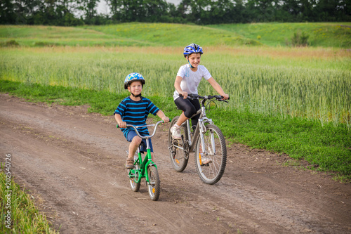Two kids riding on bikes on rural road