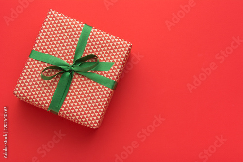 Hands holding wrapped gift box with colored ribbon as a present for Christmas, new year, mother's day, anniversary, birthday, party,  on white background, top view. Present for a colleague at work.