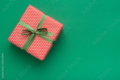 Hands holding wrapped gift box with colored ribbon as a present for Christmas, new year, mother's day, anniversary, birthday, party,  on white background, top view. Present for a colleague at work.