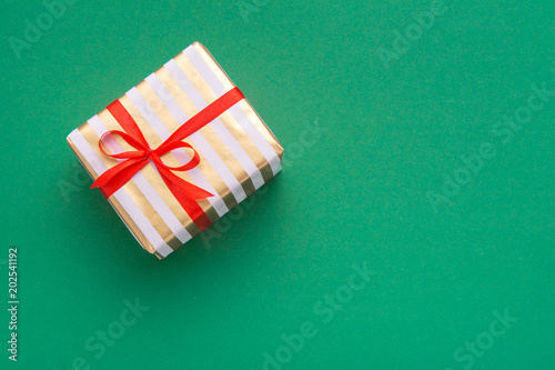 Hands holding wrapped gift box with colored ribbon as a present for Christmas, new year, mother's day, anniversary, birthday, party, on white background, top view. Present for a colleague at work.