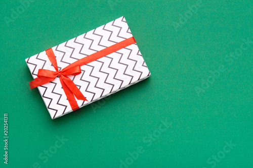 Hands holding wrapped gift box with colored ribbon as a present for Christmas, new year, mother's day, anniversary, birthday, party,  on white background, top view. Present for a colleague at work.
