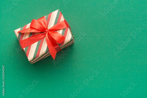 Hands holding wrapped gift box with colored ribbon as a present for Christmas, new year, mother's day, anniversary, birthday, party,  on white background, top view. Present for a colleague at work.