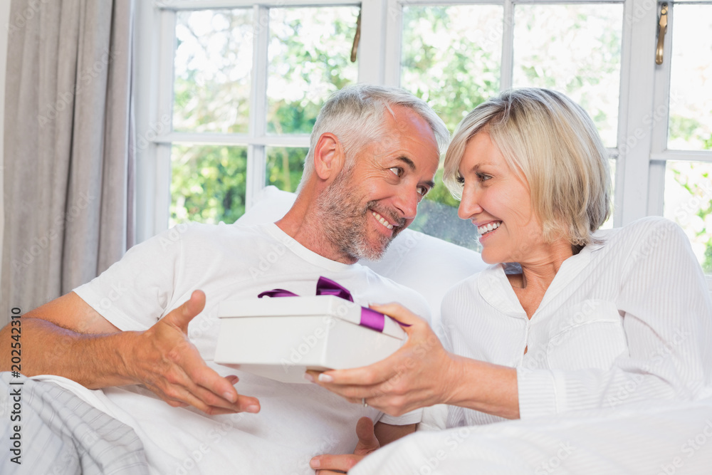 Woman giving mature man a gift box Woman giving mature man a gift box