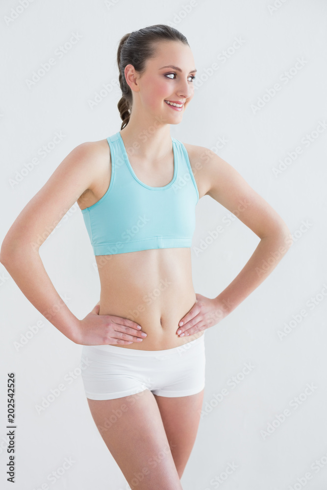 Toned young woman standing against wall Toned young woman standing against wall