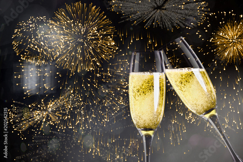 Champagne glasses clinking against colourful fireworks exploding on black background