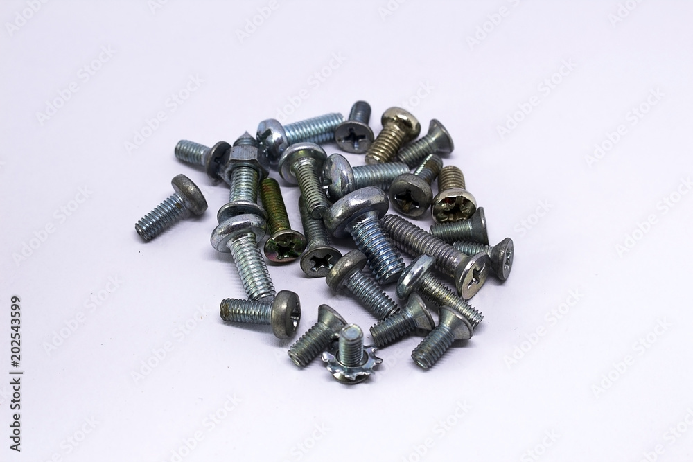 Many small bolts, screws of different colors, on a white background Many small bolts, screws of different colors, on a white background