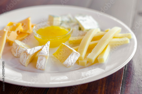 Cheese plate. Assortment of various types of cheese on wooden cutting board.