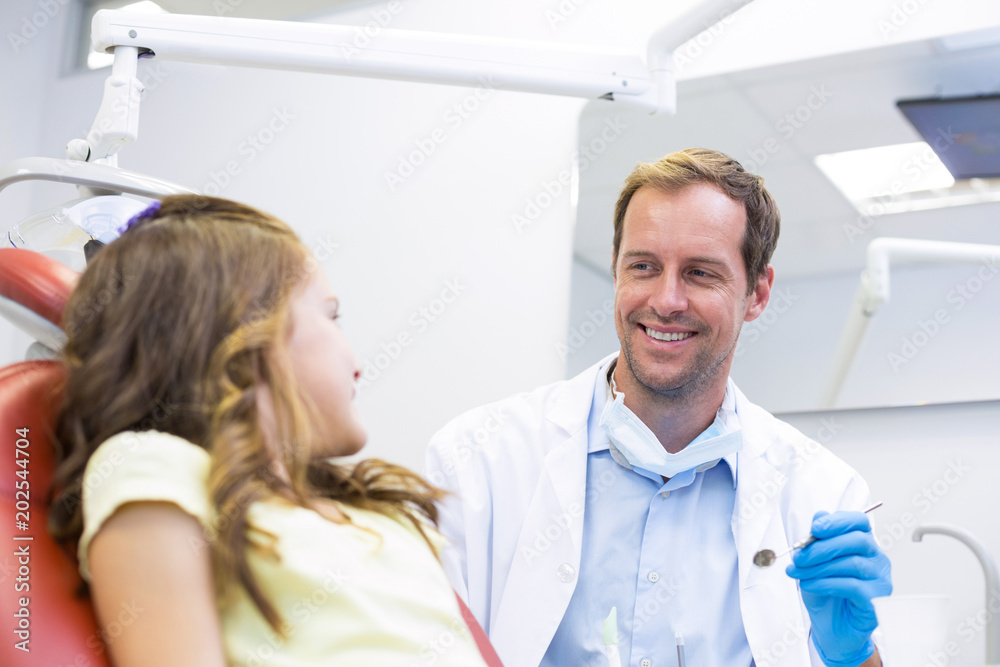 Fototapeta premium Smiling dentist talking to young patient