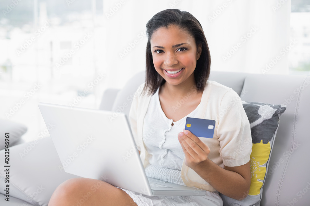 Pleased young dark haired woman in white clothes shopping online with a laptop Pleased young dark haired woman in white clothes shopping online with a laptop