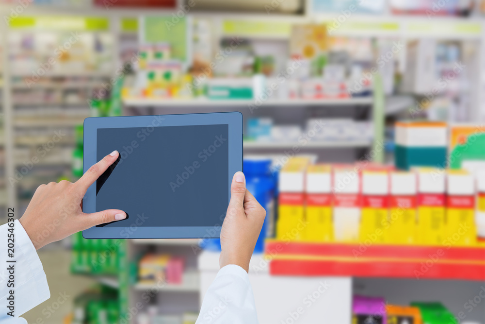 Doctor using tablet pc against close up of shelves of drugs Doctor using tablet pc against close up of shelves of drugs