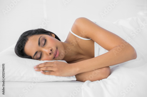 Content sleeping woman lying under the cover on her bed