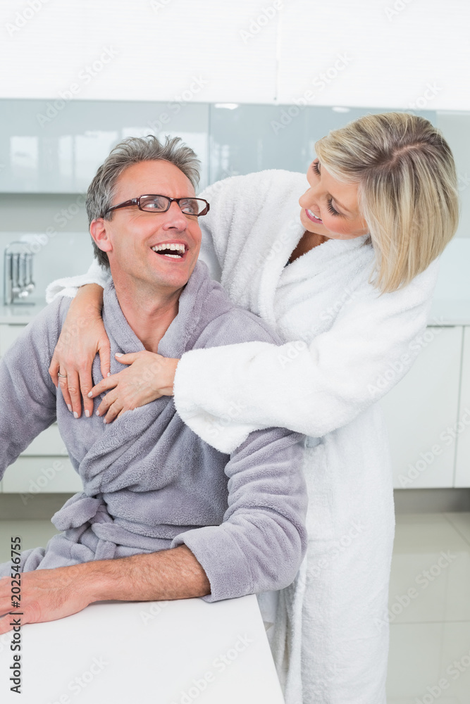 Woman embracing a man from behind in kitchen Woman embracing a man from behind in kitchen