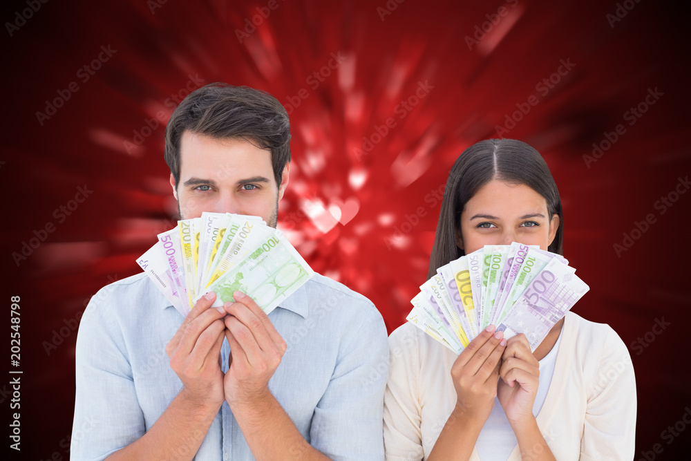 Εκτύπωση καμβά Happy couple showing their money against valentines heart design