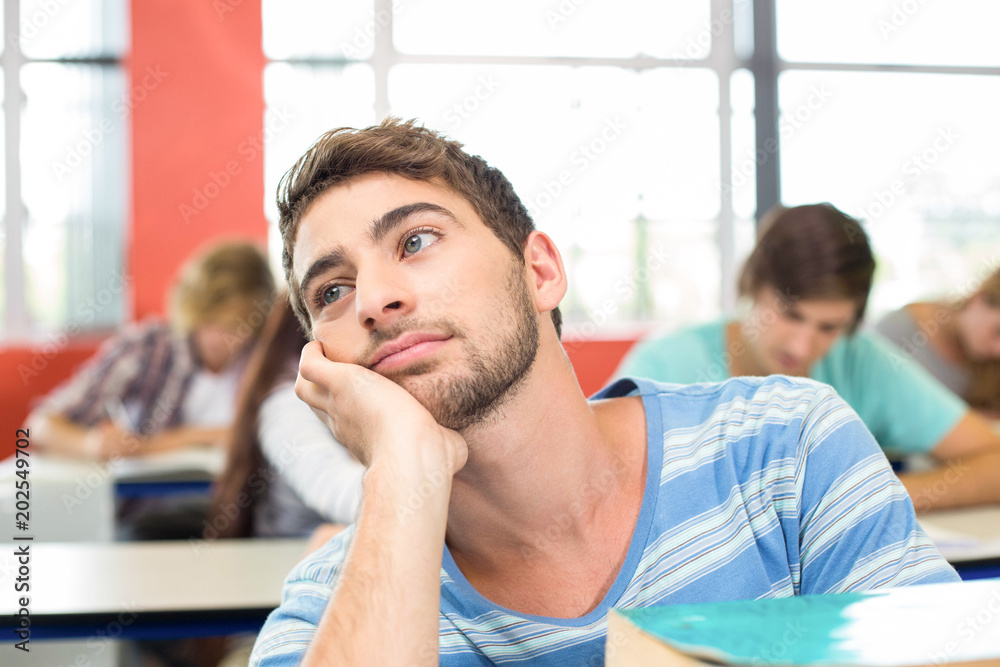Thoughtful student with books in classroom Thoughtful student with books in classroom