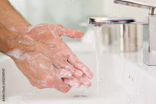 Foto Washing hands with soap under running water