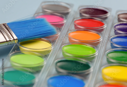 Closeup of colorful watercolor paints and blue brush