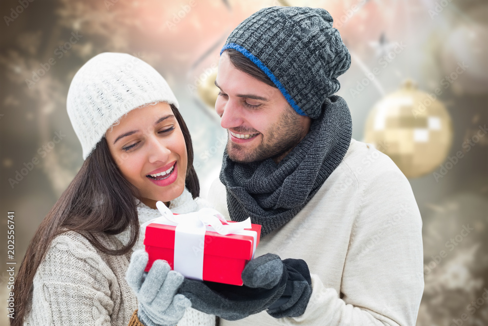 Winter couple holding gift against blurred christmas background Winter couple holding gift against blurred christmas background