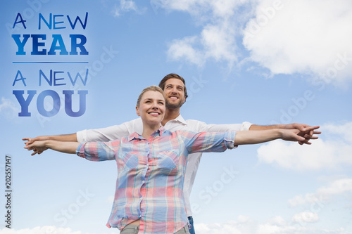Happy couple standing outside with arms stretched against new year new you