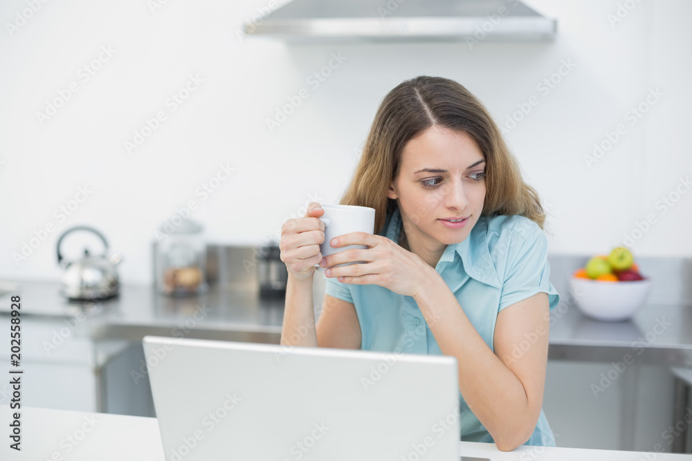 Lovely woman standing in her kitchen holding a cup Lovely woman standing in her kitchen holding a cup