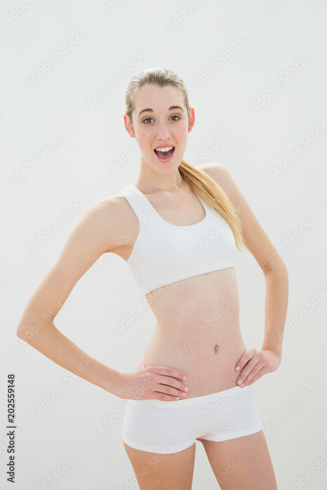 Cute sporty woman posing with hands on hips wearing sportswear