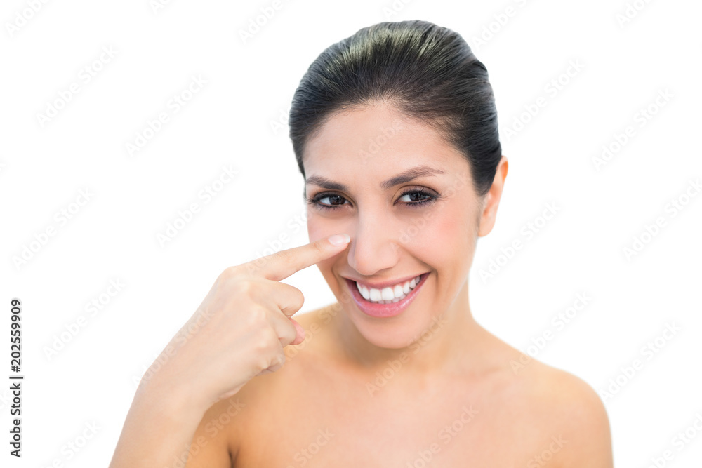 Smiling brunette pointing to nose and looking at camera Smiling brunette pointing to nose and looking at camera