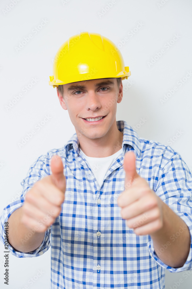 Smiling handyman in yellow hard hat gesturing thumbs up