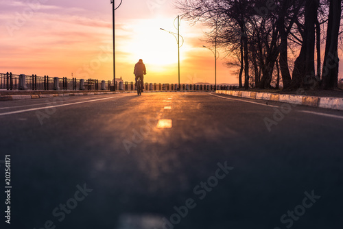 Silhouette of cyclist riding down the road