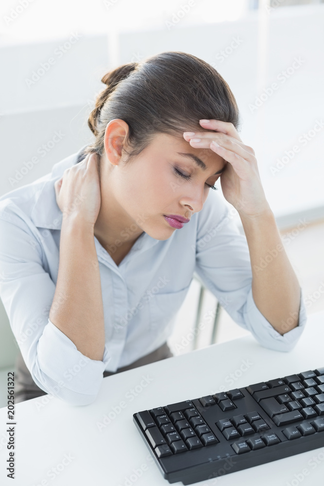 Businesswoman suffering from headache in front of laptop Businesswoman suffering from headache in front of laptop