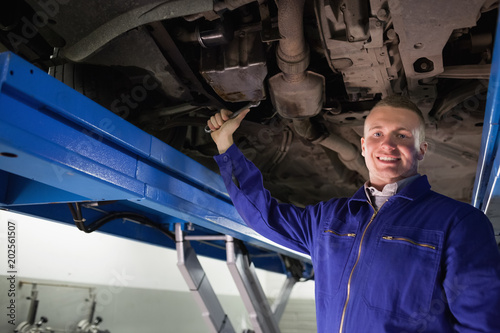 Smiling mechanic repairing with a spanner