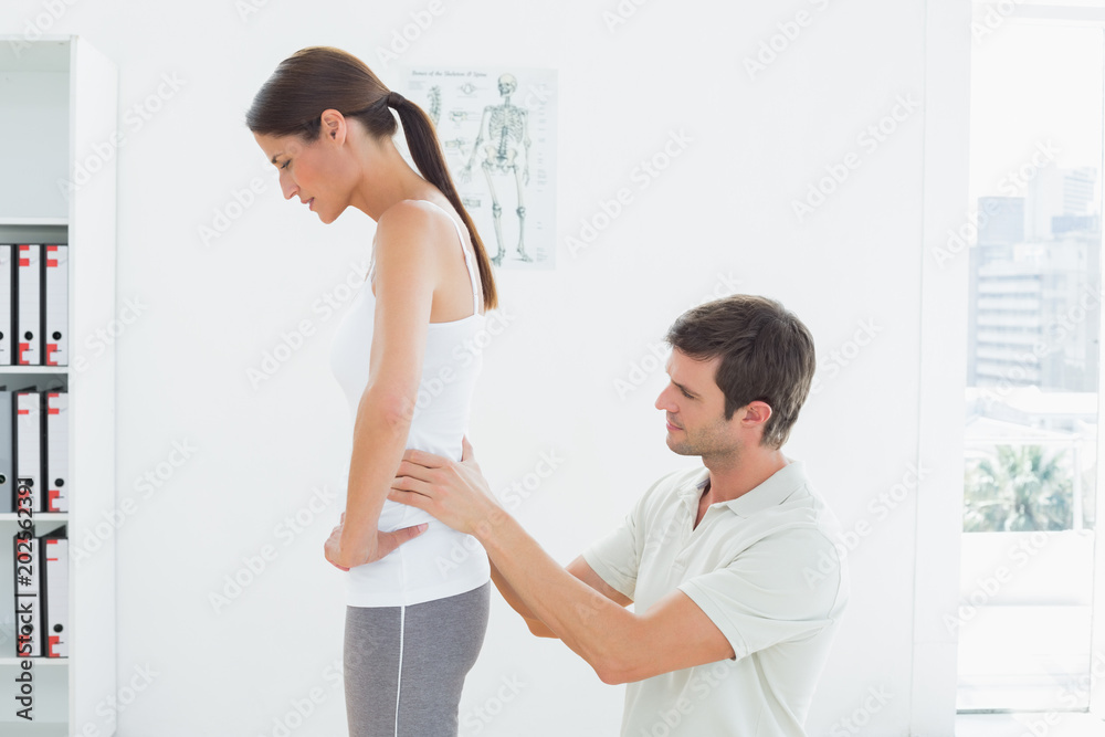 Physiotherapist examining womans back in medical office
