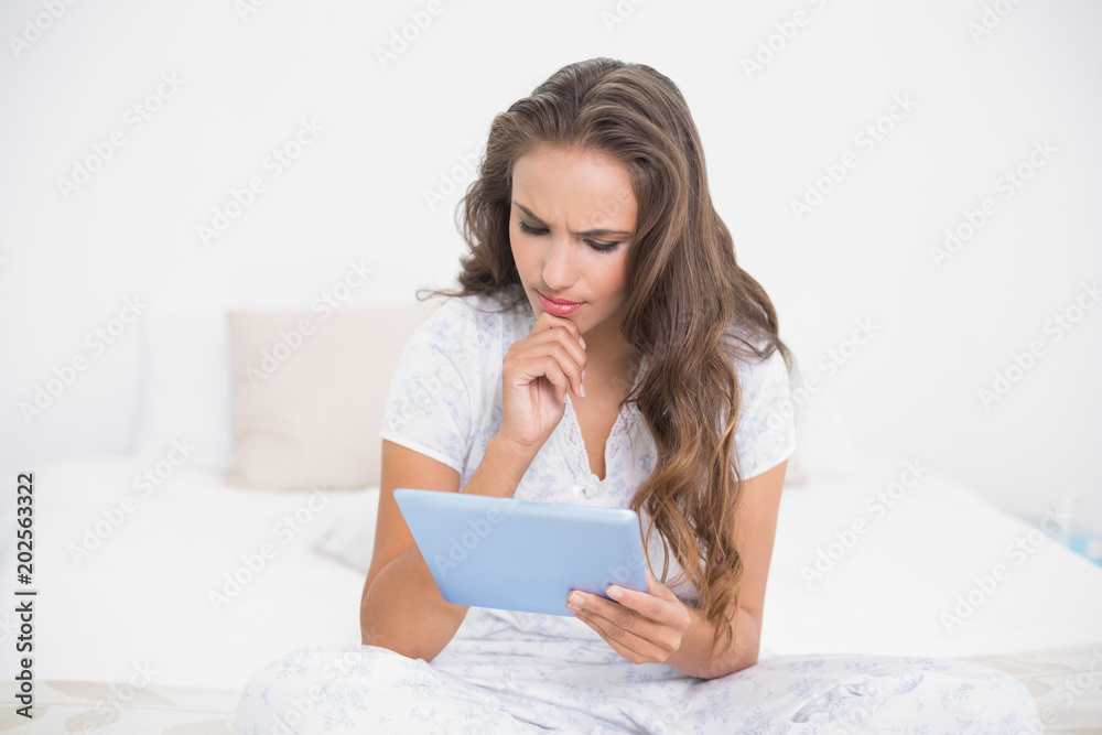 Thoughtful attractive brunette using a tablet Thoughtful attractive brunette using a tablet