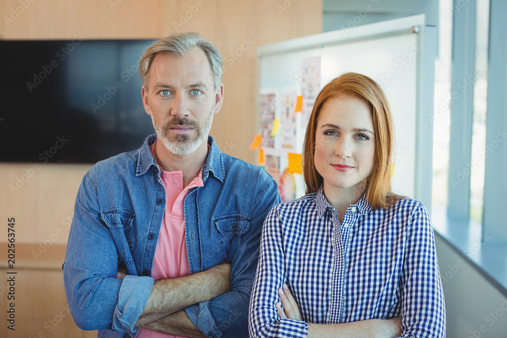 Fototapeta premium Portrait of male and female executives standing with arms crossed in conference room