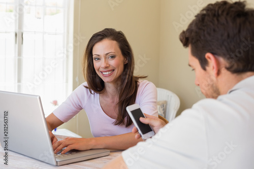 Couple using laptop and cellphone at home