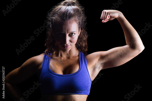Portrait of confident female athlete flexing muscles